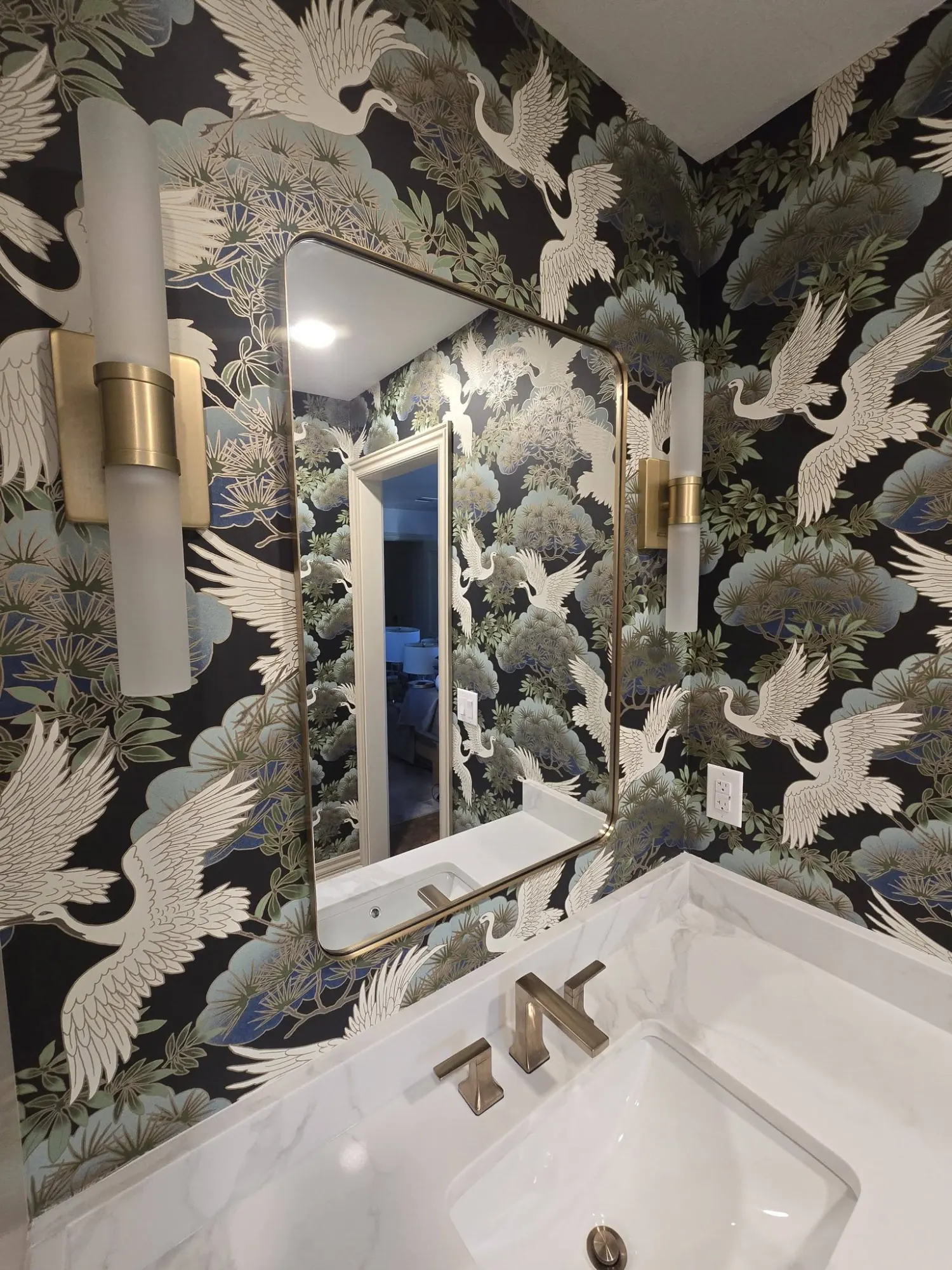 Powder room with crane wallpaper and brass fixtures