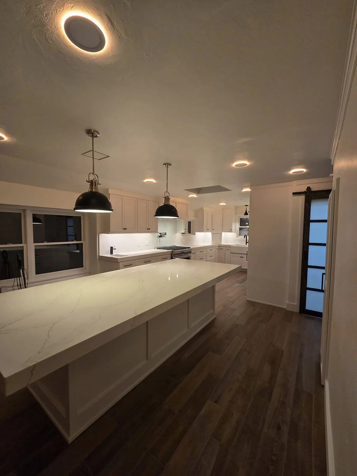 Warm white kitchen with oversized island and black pendants