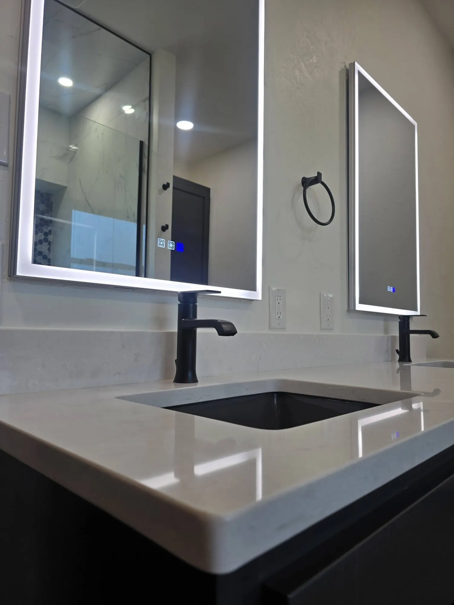 Black sink, illuminated mirror, and quartz vanity detail in a finished Edmond bathroom